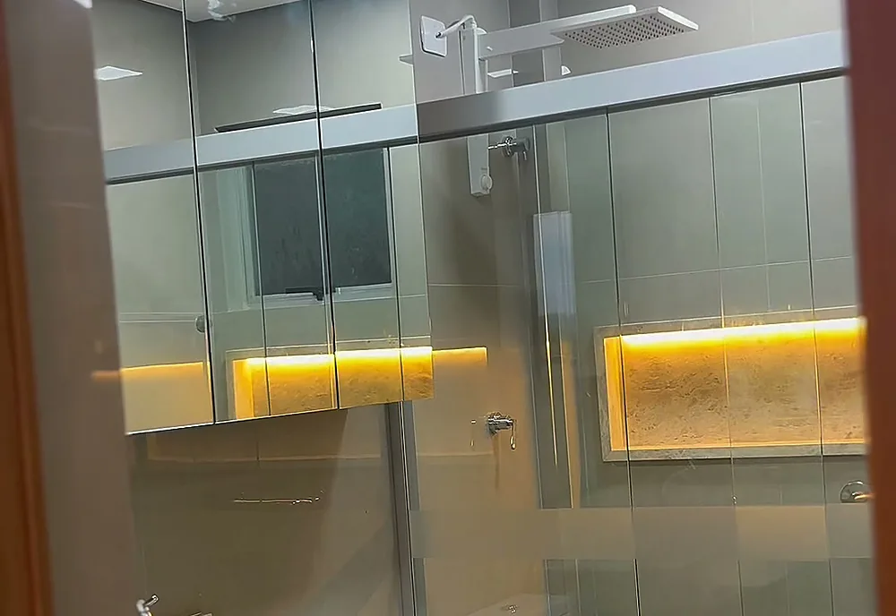 Banheiro de suíte com box de vidro, bancada em pedra e marcenaria, entregue em reforma da Si.Go